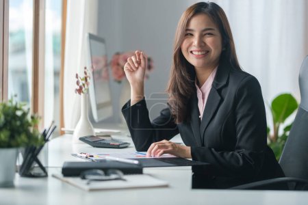 Foto de Hermosa gestora femenina usando computadora portátil y documento financiero de trabajo en su estación de trabajo. - Imagen libre de derechos