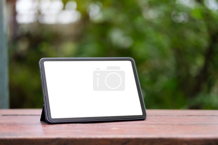 Foto de Tableta digital con pantalla blanca en mesa de madera al aire libre. Pantalla en blanco para su mensaje de texto publicitario. - Imagen libre de derechos