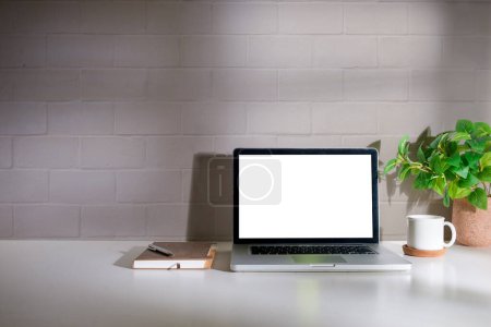 Foto de Escritorio de oficina con laptop, taza de café, maceta y papelería. Pantalla en blanco para su texto publicitario. - Imagen libre de derechos