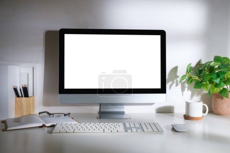Foto de Espacio de trabajo mínimo con computadora de pantalla blanca y suministros de oficina en mesa blanca. - Imagen libre de derechos
