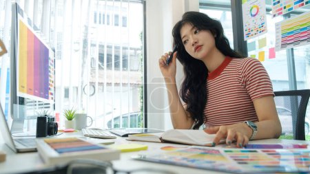 Photo for Side view of young woman sitting at graphic studio and choosing color for creative project on computer screen. - Royalty Free Image