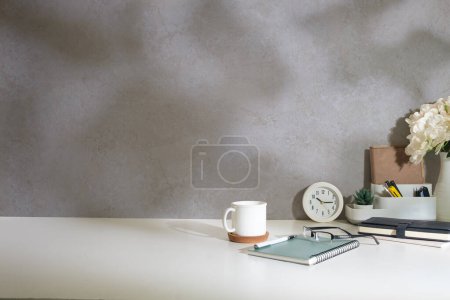 Photo for Minimal workspace with book, coffee cup and pencil holder on white table. Copy space for your advertising text. - Royalty Free Image