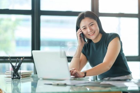 Photo for Attractive asian businesswoman talking with her business partner while sitting in modern office. - Royalty Free Image
