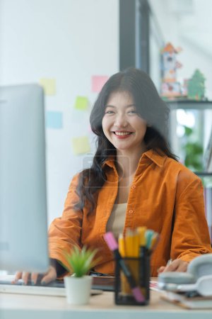 Foto de Joven mujer asiática diseñador gráfico trabajando con muestras de muestras de muestras de color en la oficina moderna. - Imagen libre de derechos