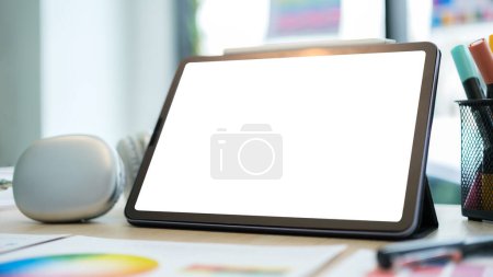 Téléchargez les photos : Tablette numérique avec écran vide, casque et échantillons d'échantillons d'échantillons d'échantillons de couleur sur la table en bois. espace de travail graphiste. - en image libre de droit
