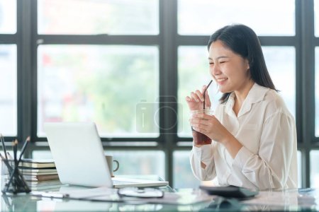 Téléchargez les photos : Professional female accountant holding coffee and checking financial reports. - en image libre de droit
