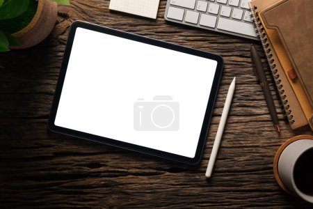 Foto de Vista superior de la tableta digital con pantalla vacía, taza de café, portátil y teclado en la mesa de madera. - Imagen libre de derechos