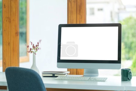 Foto de Lugar de trabajo contemporáneo con pantalla en blanco monitor de ordenador, taza de café y libros. - Imagen libre de derechos