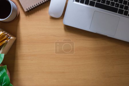 Photo for Wooden working desk with laptop computer, mouse, coffee cup and stationery . Top view with copy space. - Royalty Free Image