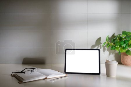 Photo for Digital tablet with empty display, glasses, notebook and coffee cup in white table. - Royalty Free Image