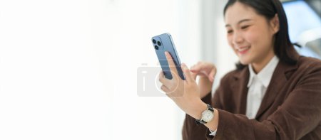 Photo for Close up view female employee taking a break from work and using mobile phone. - Royalty Free Image