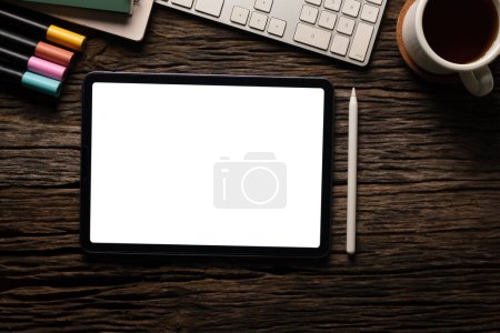 Foto de Tableta digital plana con pantalla en blanco, taza de café y papelería en la mesa de madera. Lugar de trabajo moderno. - Imagen libre de derechos