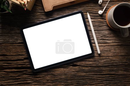 Foto de Tableta digital plana, vista superior con pantalla en blanco, computadora portátil, taza de café y libro en mesa de madera. - Imagen libre de derechos