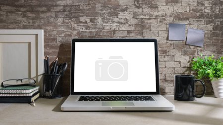 Téléchargez les photos : Ordinateur portable maquette, tasse à café, livres et porte-crayon sur table blanche avec mur de briques. - en image libre de droit