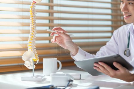 Téléchargez les photos : Orthopédiste masculin expérimenté pointant vers le modèle de colonne vertébrale humaine à la clinique. Concept médical, orthopédique et de santé. - en image libre de droit