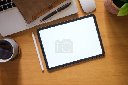 Foto de Top view of digital tablet, glasses, coffee cup and notebook on wooden table. Blank screen for advertise text. - Imagen libre de derechos