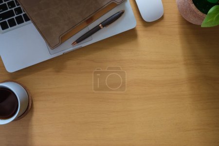 Foto de Ordenador portátil, libro, taza de café y planta de interior en la mesa de madera. Vista superior con espacio de copia. - Imagen libre de derechos