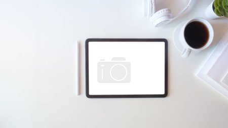 Foto de Tableta plana, vista superior digital con pantalla en blanco, computadora portátil, taza de café y libro en la mesa. - Imagen libre de derechos