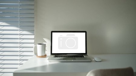 Foto de Ordenador portátil con pantalla en blanco, planta en maceta, marco de imagen y artículos de papelería en la mesa blanca. - Imagen libre de derechos