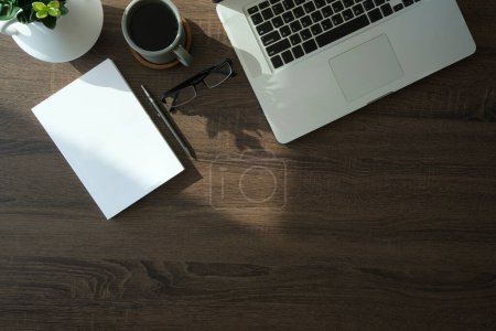 Photo for Top view laptop computer, glasses and coffee cup on wooden table. - Royalty Free Image