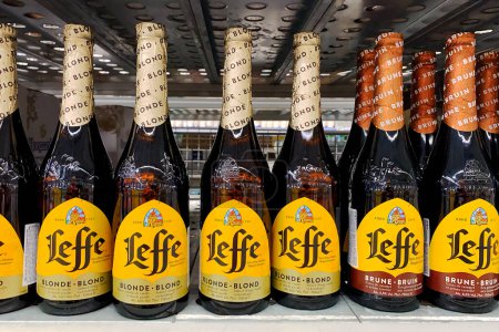 Foto de Kiev, Ucrania 28.07.2023: - Leffe marca de cerveza apilados en botellas de plástico en el estante en el supermercado. Envase de muchas botellas de cerveza en el departamento de alcohol. - Imagen libre de derechos