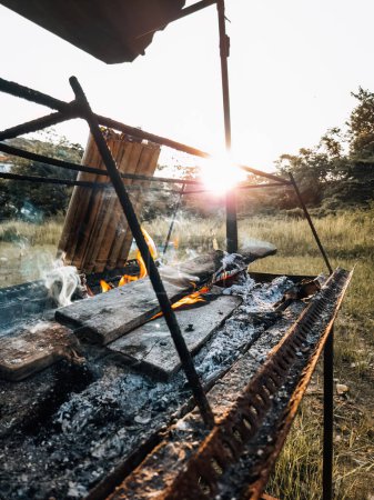 Téléchargez les photos : Feu brûlant le bois pendant la cuisson lemang sur le coucher du soleil. - en image libre de droit
