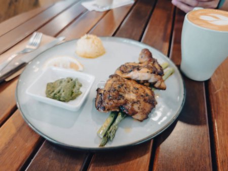Téléchargez les photos : Blurry photo of the chicken grilled served on the plate at a cafe. Defocused for copy space. - en image libre de droit