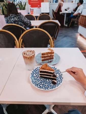 Téléchargez les photos : Putrajaya, Malaisie - 8 juin 2022 Gâteaux de velours rouge et de carotte sur la table avec latte glacé pour l'heure du thé dans le centre commercial IOI City. - en image libre de droit