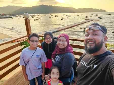 Foto de Familia musulmana malaya tomando foto de autorretrato mientras viaja de vacaciones en la playa de Malasia. - Imagen libre de derechos