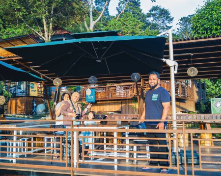 Téléchargez les photos : Perak, Malaisie - Oct 19, 2022 Famille debout sur la terrasse du patio en bois dans Kuak Hill Resort à Lenggong. - en image libre de droit