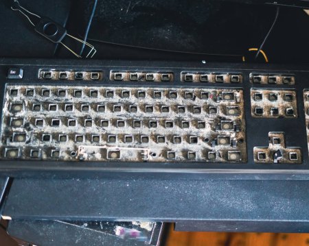 Schmutzige Qwerty-Tastatur voller Staub und Unrat auf dem Tisch. Reinigung des Computers.