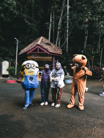Perlis, Malaysia - Aug 6, 2022; Hijab women with two mascots at the entrance of Gua Kelam or cave or darkness entrance.