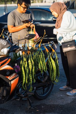 Foto de Cameron Highlands, Malasia - 15-sep-2022 Clientes que compran el vendedor Parkia speciosa o comúnmente conocido como "Petai" en el mercado matutino. - Imagen libre de derechos