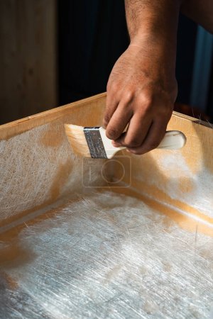 Bürstlösung durch Glasfaserplatten auf einer Holzkiste. Ein Diy-Projekt zu Hause.