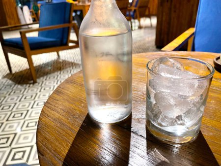 Téléchargez les photos : Vodka fraîche rafraîchissante dans la bouteille avec des roches de glace dans le verre servi dans le pub bonne liqueur dans les happy hours - en image libre de droit
