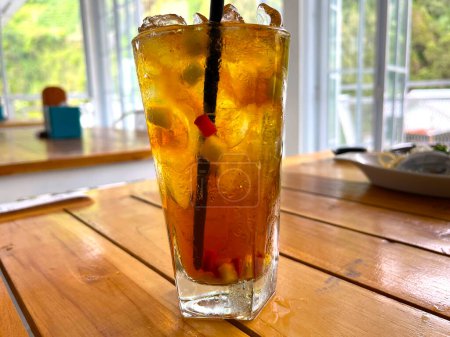 Téléchargez les photos : Cocktail de fruits frais boisson alcoolisée avec rhum et whisky dans un verre clair et morceau de glace sur un fond de table en bois - en image libre de droit