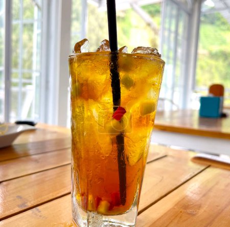 frisch gemixter Fruchtcocktail-Alkohol-Drink mit Rum und Whiskey in einem klaren Glas und Eisbrocken auf einem hölzernen Tischhintergrund