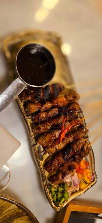 Homemade beef Satay marinated with spice and sweet soy sauce, coriander beef satay, served on plate with onion, chilli, soy sauce and tomato. Indonesian traditional food