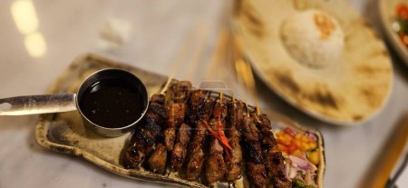 Homemade beef Satay marinated with spice and sweet soy sauce, coriander beef satay, served on plate with onion, chilli, soy sauce and tomato. Indonesian traditional food
