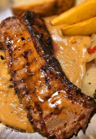 Foto de Nueva york tira lomo carne de res carne de res con salsa de champiñones y cuñas de patata y ensalada chapada en un hermoso plato en una casa de filetes - Imagen libre de derechos