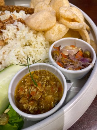 Nasi uduk ayam bakar, or coconut milk flavor rice served with grilled chicken, fresh salad, and chili paste traditional Indonesian food, indonesian street food, homemade food
