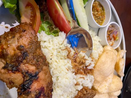 Nasi uduk ayam bakar, oder Kokosmilch-Aroma-Reis, serviert mit gegrilltem Huhn, frischem Salat und Chili-Paste traditionelles indonesisches Essen, indonesisches Streetfood, hausgemachtes Essen