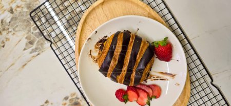 Photo for Fresh homemade striped chocolate croissant with chocolate filling on a round white plate, served with fresh strawberry, good cooking ideas - Royalty Free Image