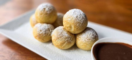 Photo for Homemade Dutch poffertjes mini pancakes with icing powdered sugar and chocolate fillings with additional chocolate sauce for delicious desserts - Royalty Free Image
