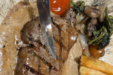 Roaststeak vom Grill medium rare serviert mit Kartoffeln und Salat mit Champignons schwarzer Pfeffer Sauce in einem Restaurant