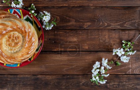 Téléchargez les photos : Pain gâteau voyage sur plaque adras décoré de fleurs de cerisier blanc sur fond en bois. Navruz, carte postale du Ramadan - en image libre de droit