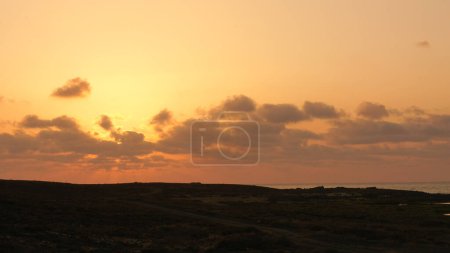 Tranquil dusk in arid landscape, coastal beauty on the horizon.
