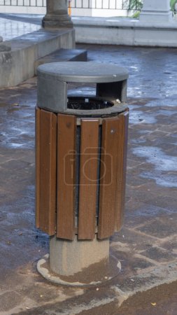 Modern urban trash bin, reflecting light on wet pavement, with eco-friendly design