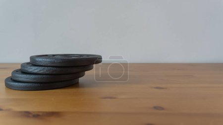 Black barbell weights on wood. Fitness, strength training, and health