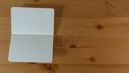 Foto de Escritorio de madera minimalista con diario en blanco, que invita a la inspiración y creatividad - Imagen libre de derechos